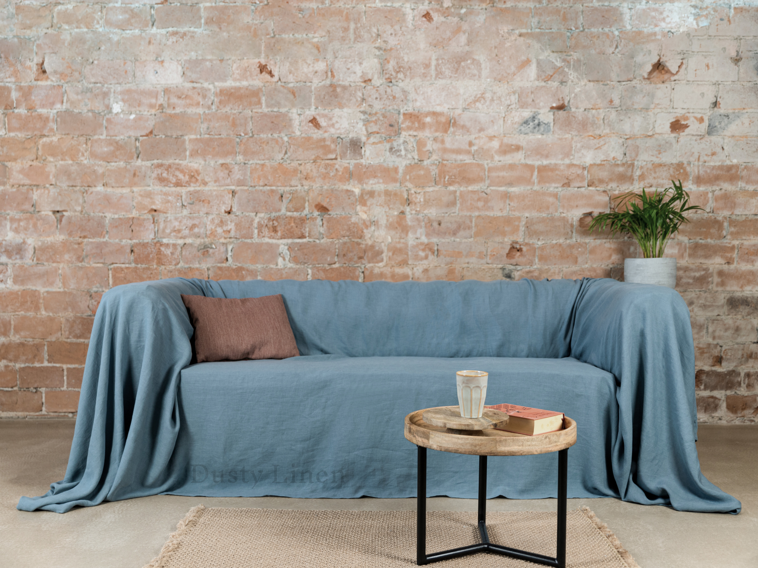 a couch covered with a blue blanket next to a table