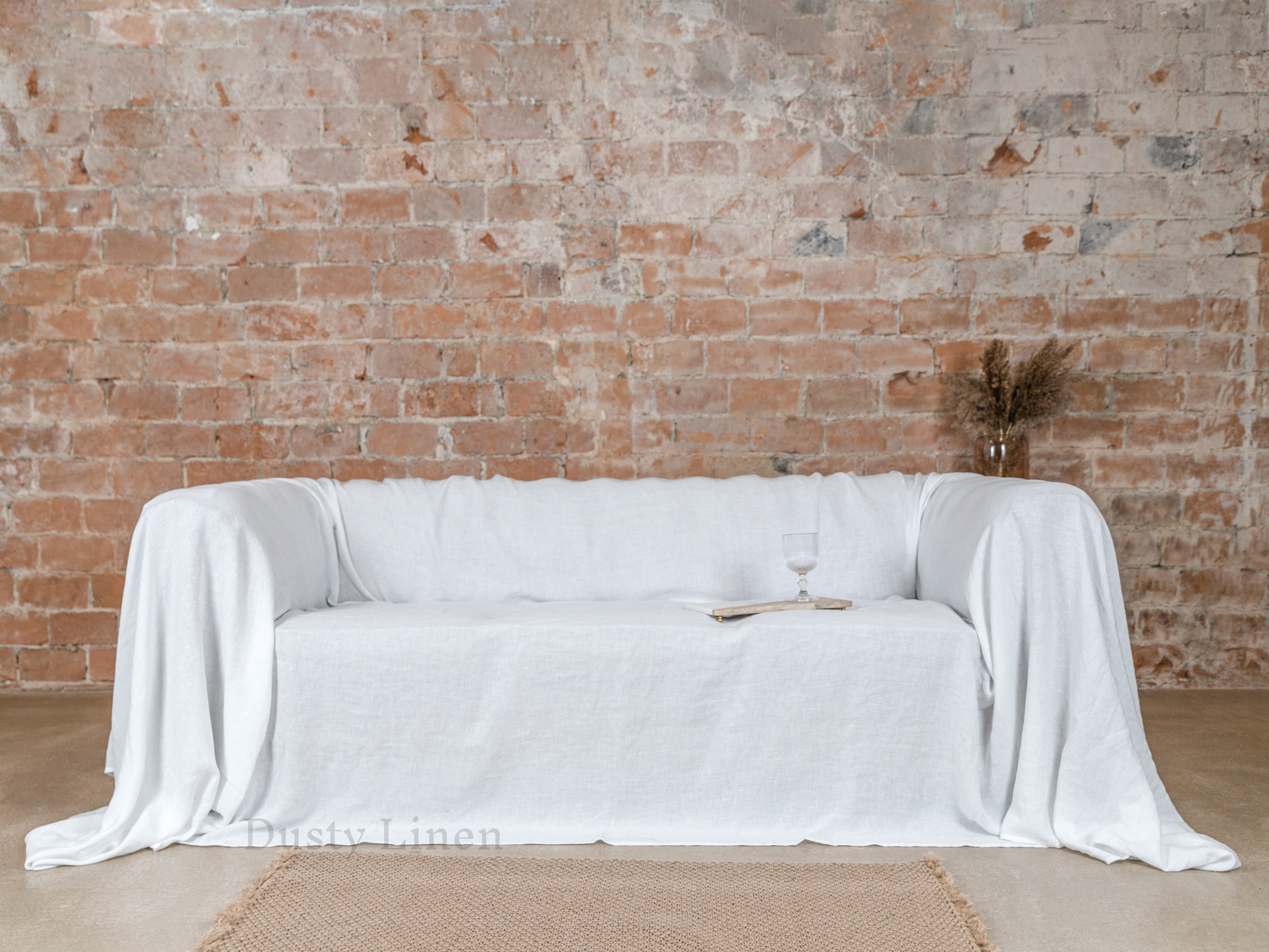 a couch covered in a white cloth next to a brick wall