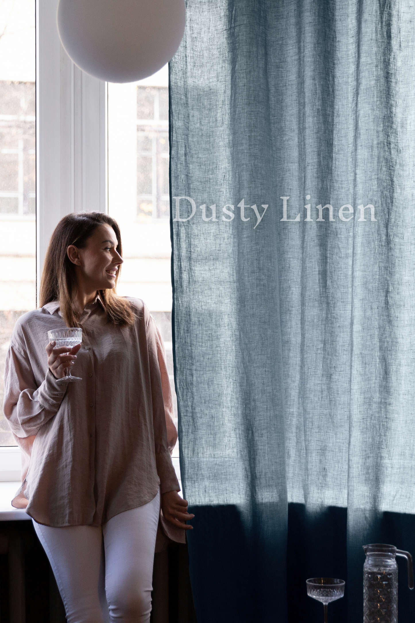 a woman standing next to a window holding a glass of wine