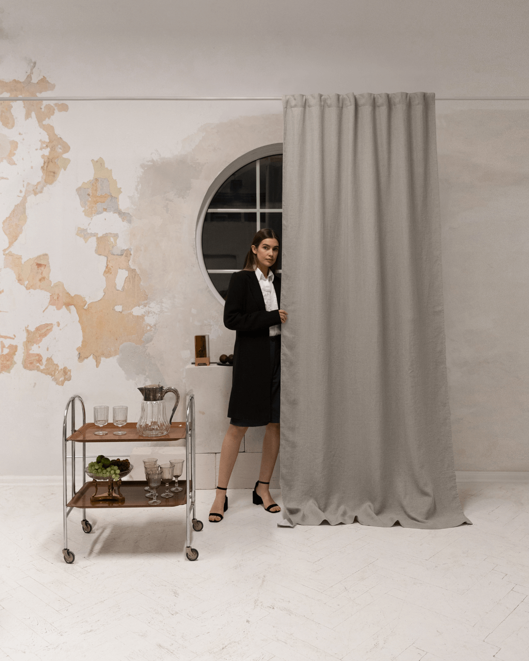 Woman standing at window with natural linen blackout curtains closed