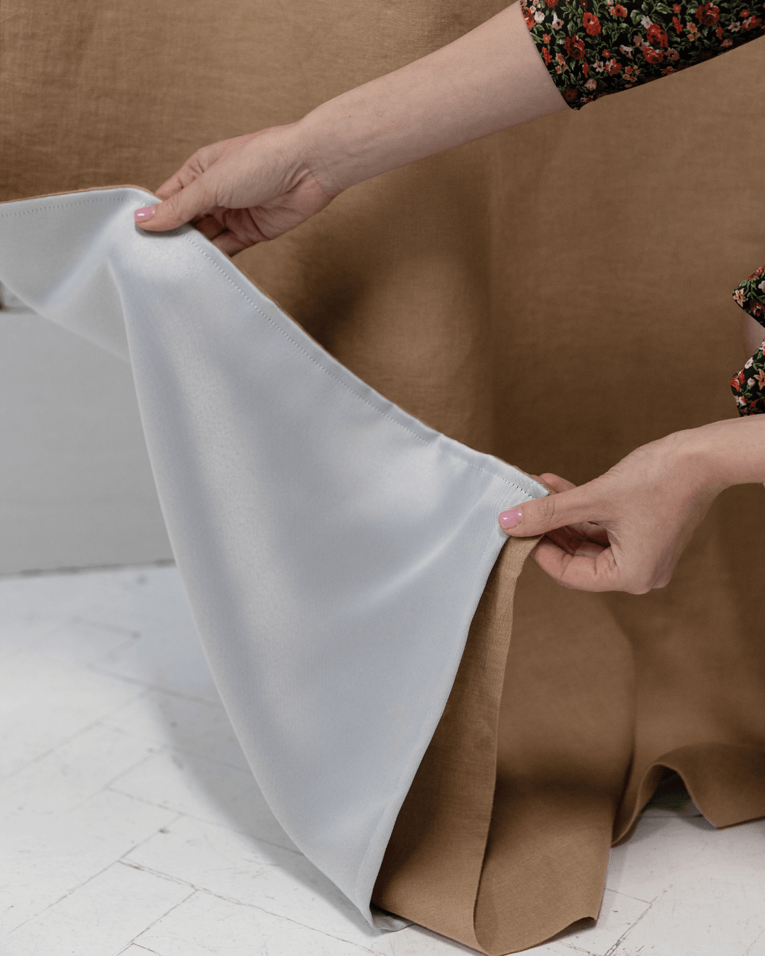 Person holding camel brown linen blackout curtain panel, showing weight and drape
