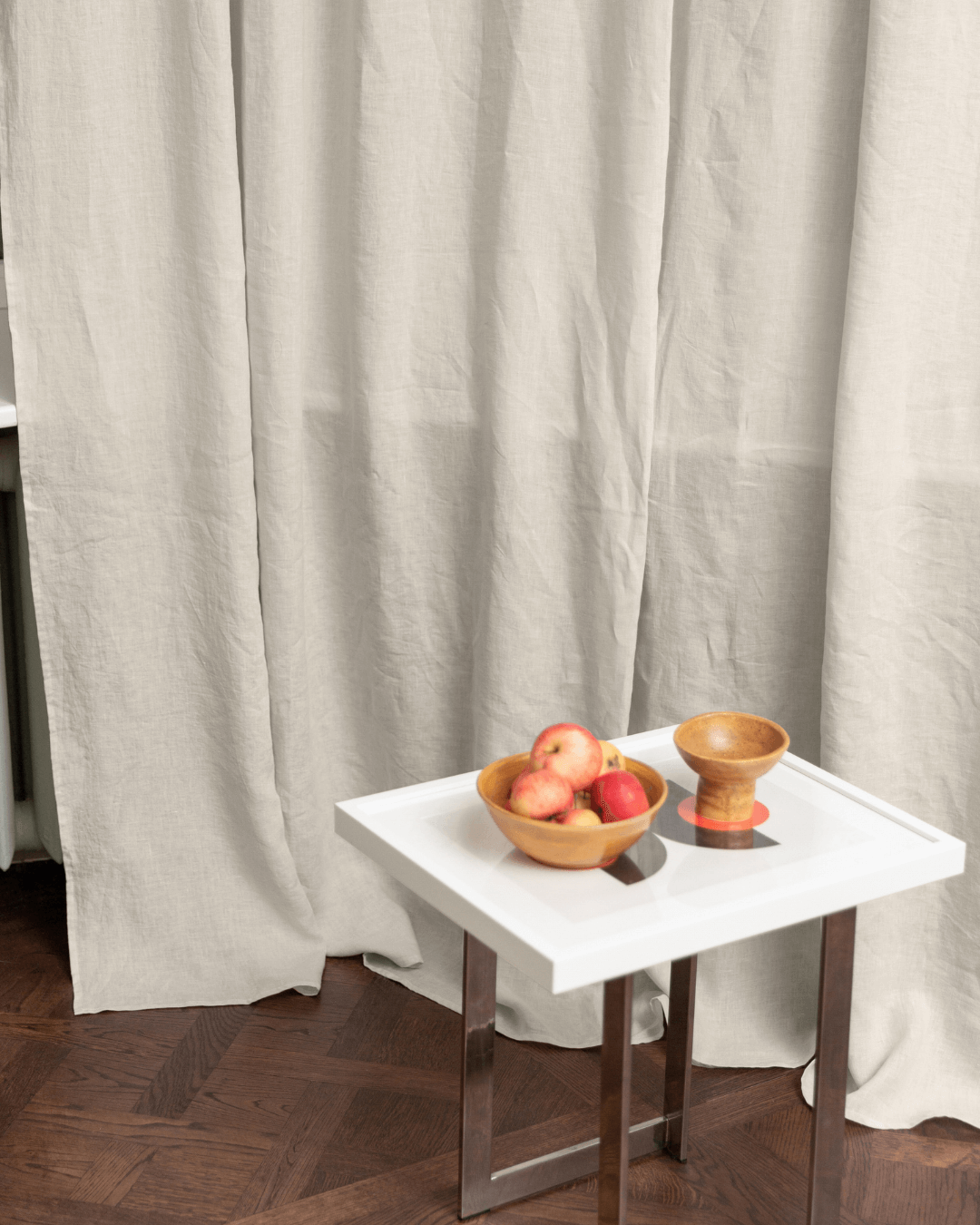 Cream linen curtains in styled interior with table and bowls