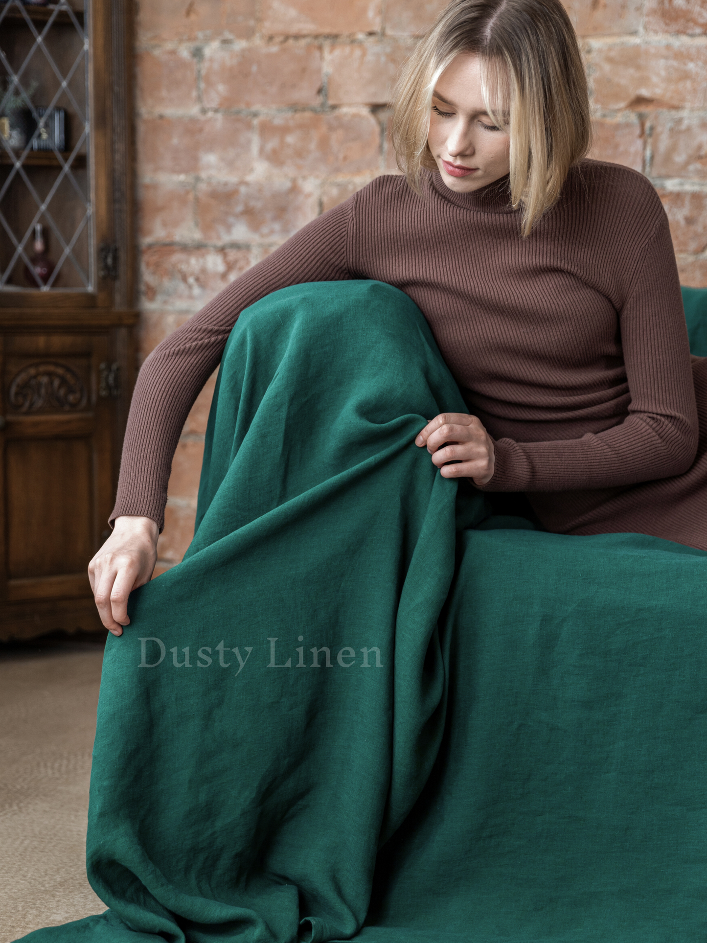 a woman is sitting on a couch wrapped in a blanket