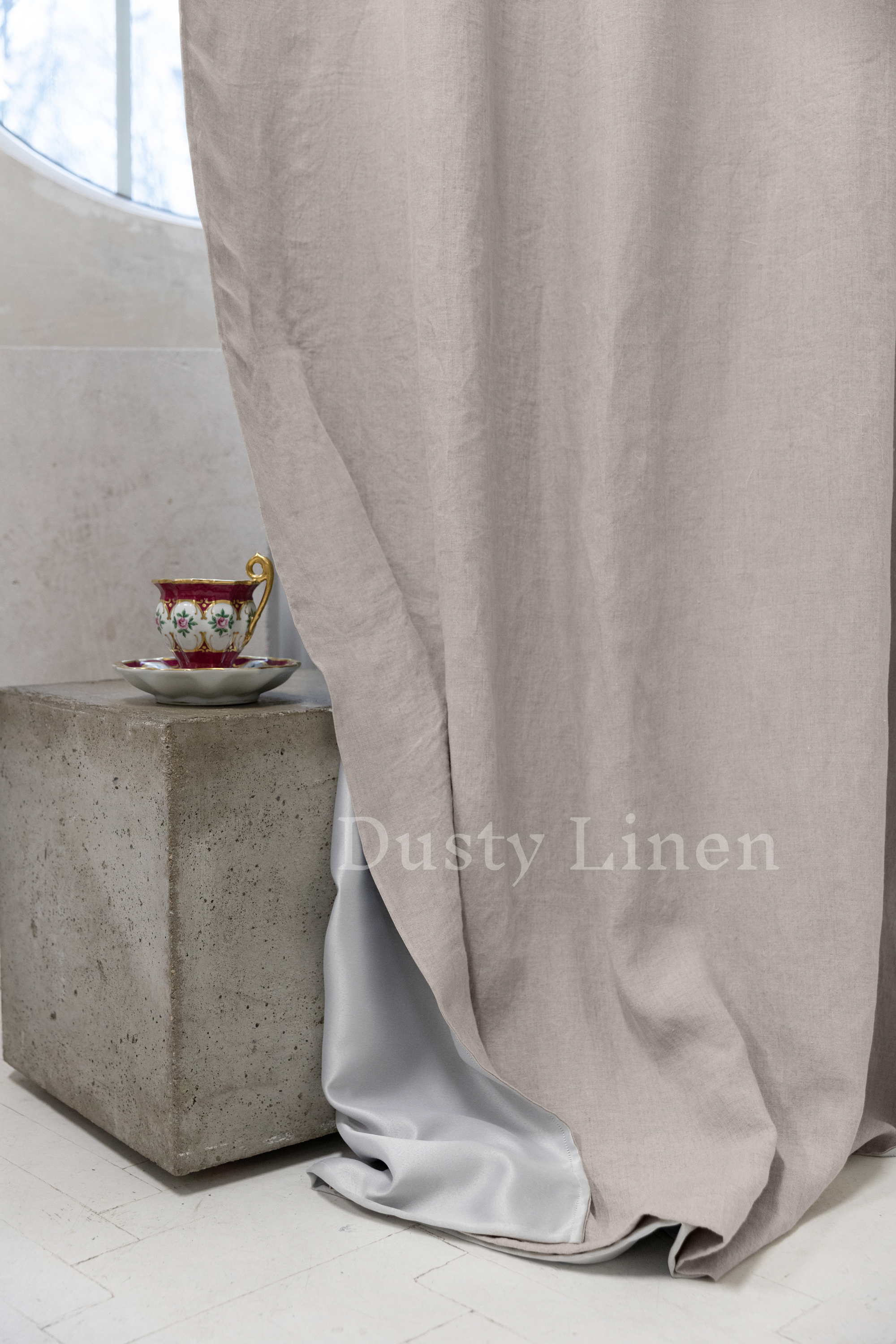 a cup and saucer sitting on a table next to a curtain