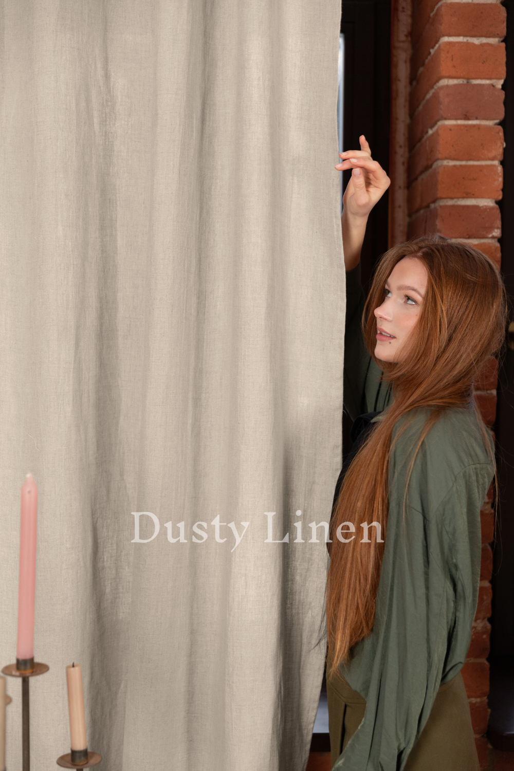 a woman standing next to a window holding a candle