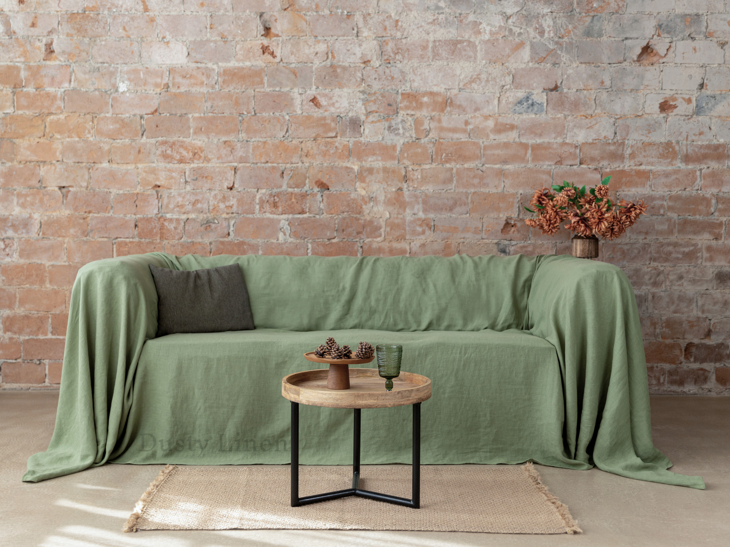 a couch covered with a green cover next to a brick wall