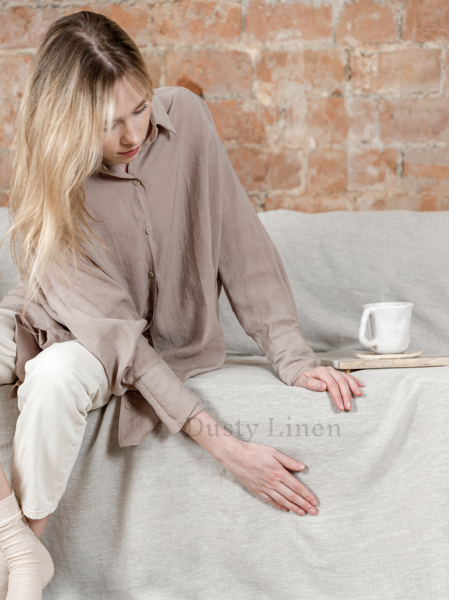 a woman sitting on a couch with a cup of coffee