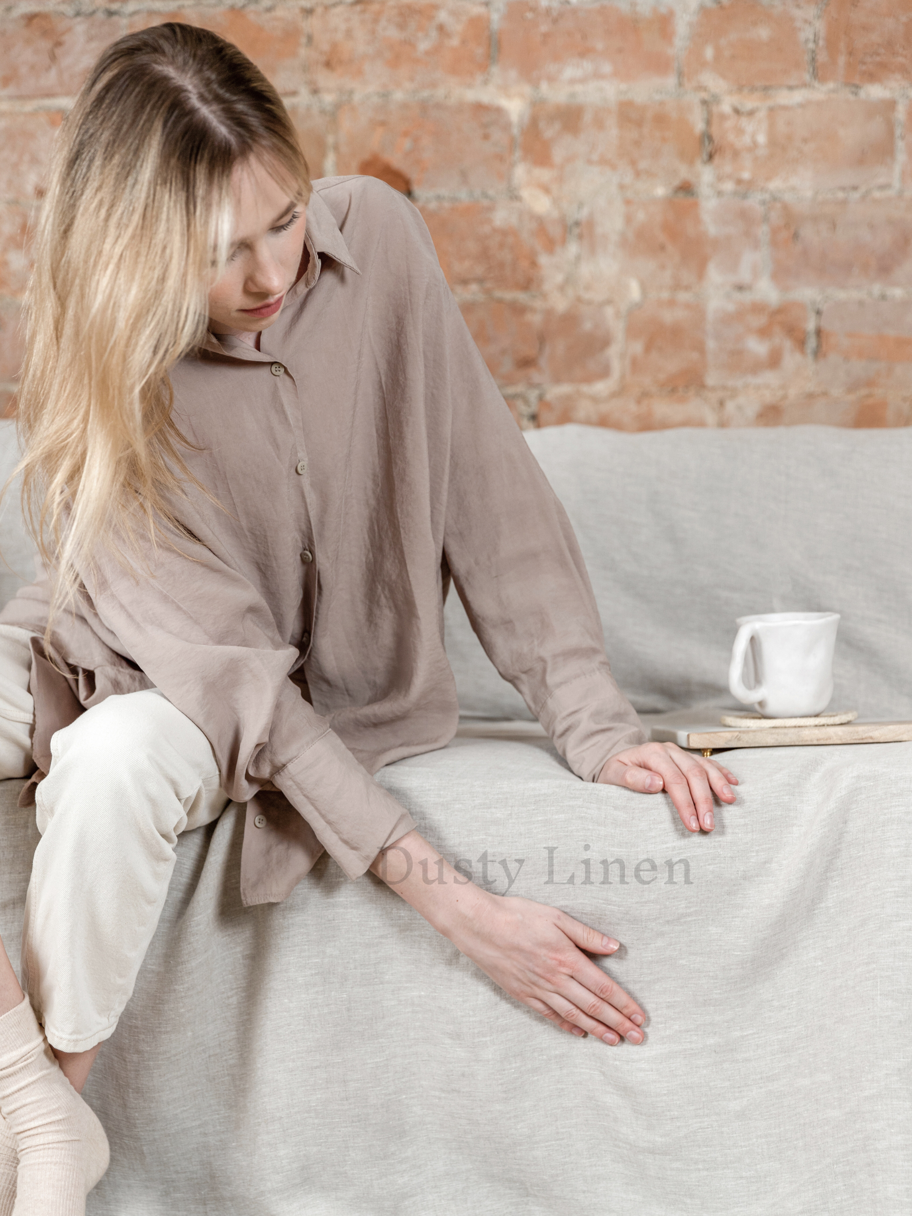 a woman sitting on a couch with a cup of coffee