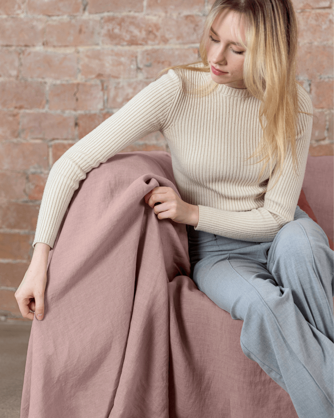 Woman sitting on sofa with dusty rose linen sofa cover