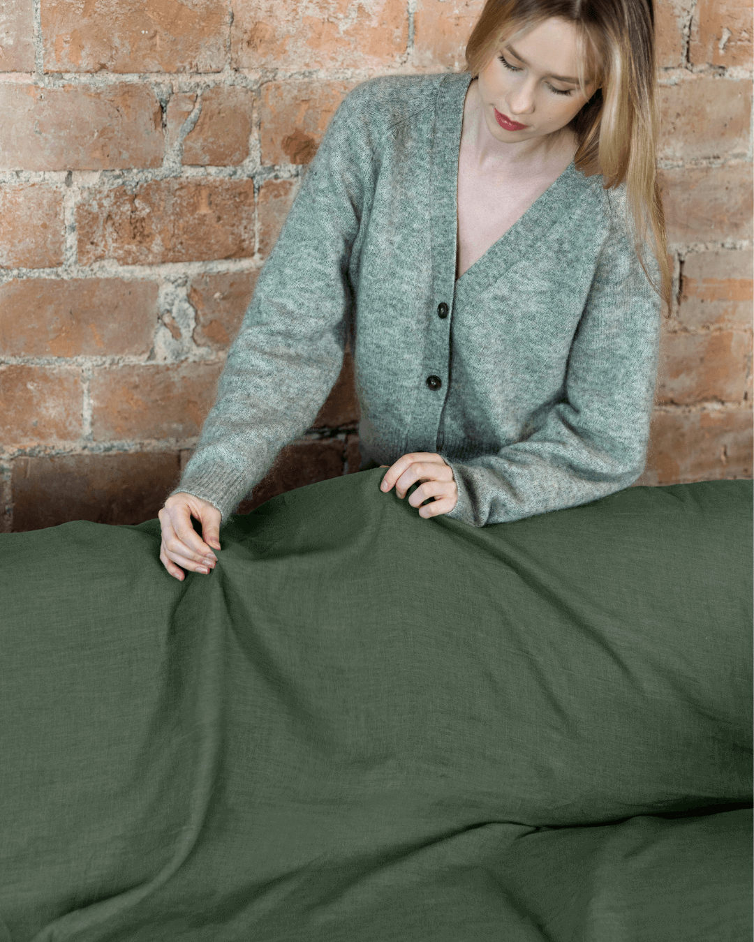 a woman in a gray cardigan laying on a bed
