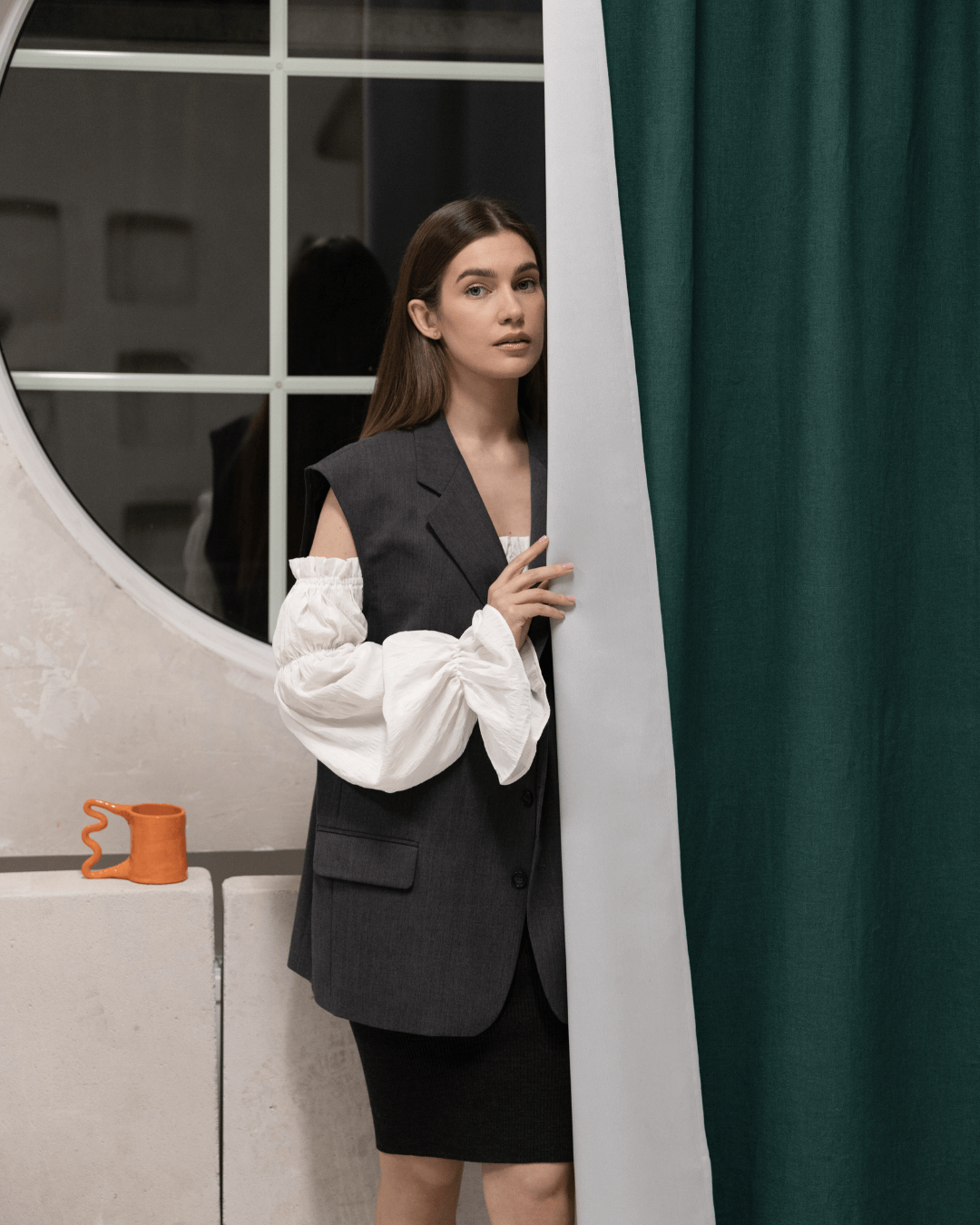 Woman behind emerald green linen blackout curtain at window