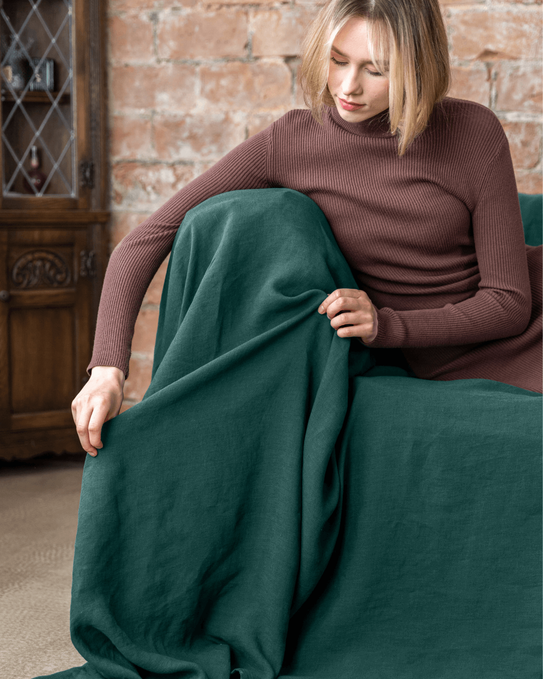 Woman on sofa with emerald green linen sofa cover loose drape