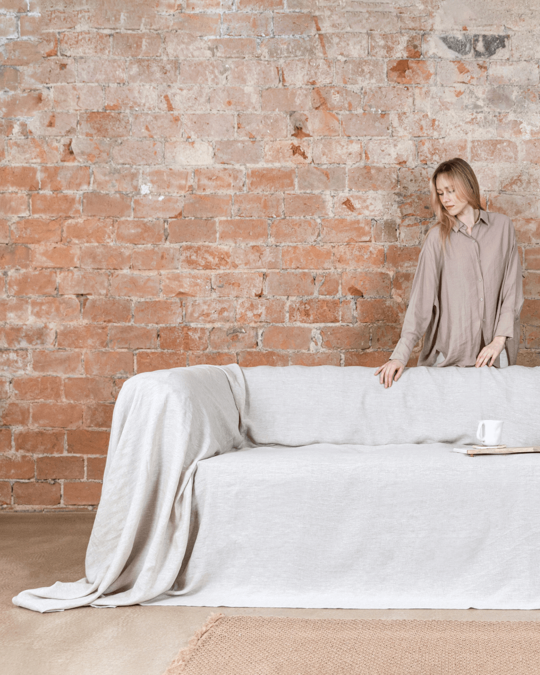a woman standing behind a couch with a white cover on it