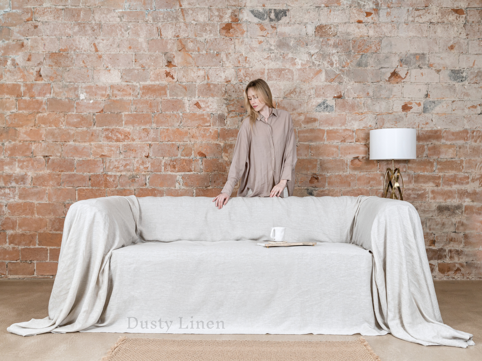 a woman standing behind a couch with a white cover on it