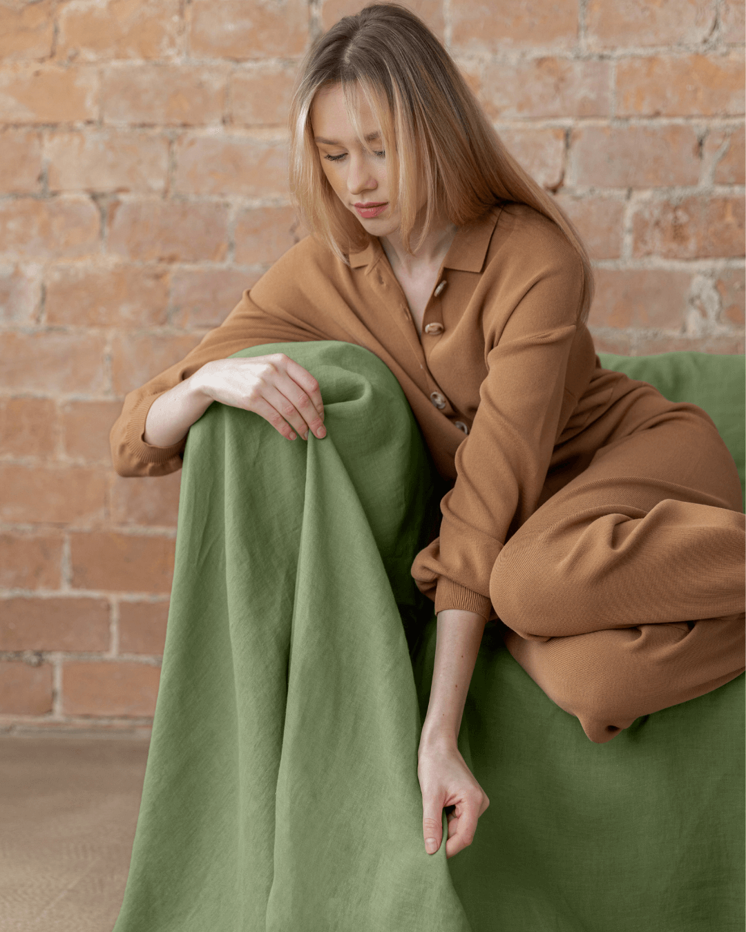 Woman sitting on sofa with khaki green linen couch cover seamless