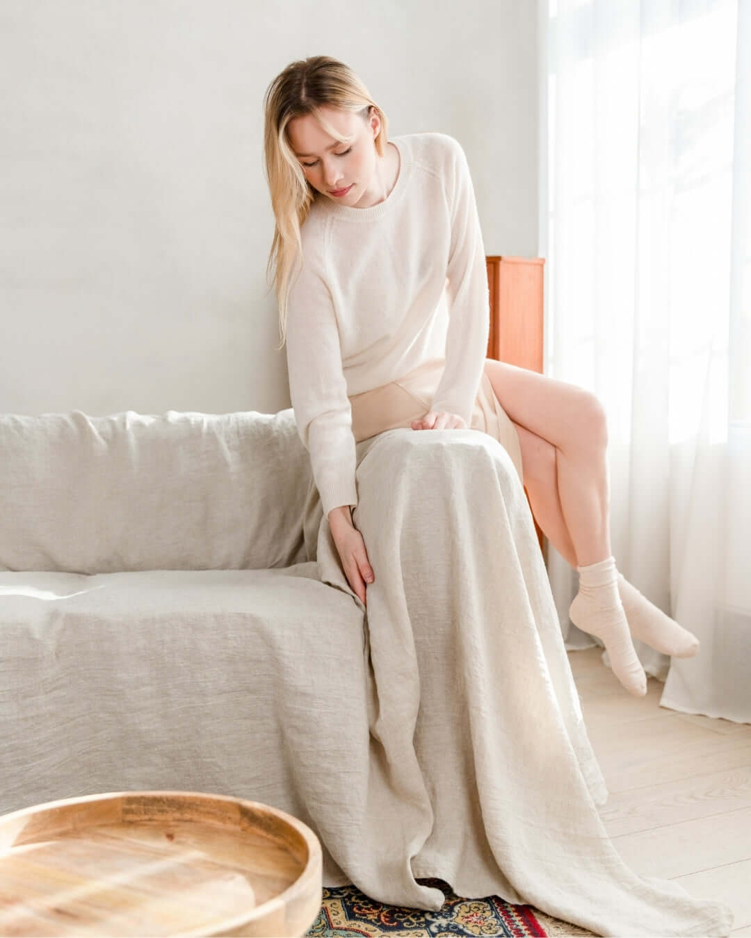 Woman on sofa with natural light linen couch slipcover, lifestyle photo