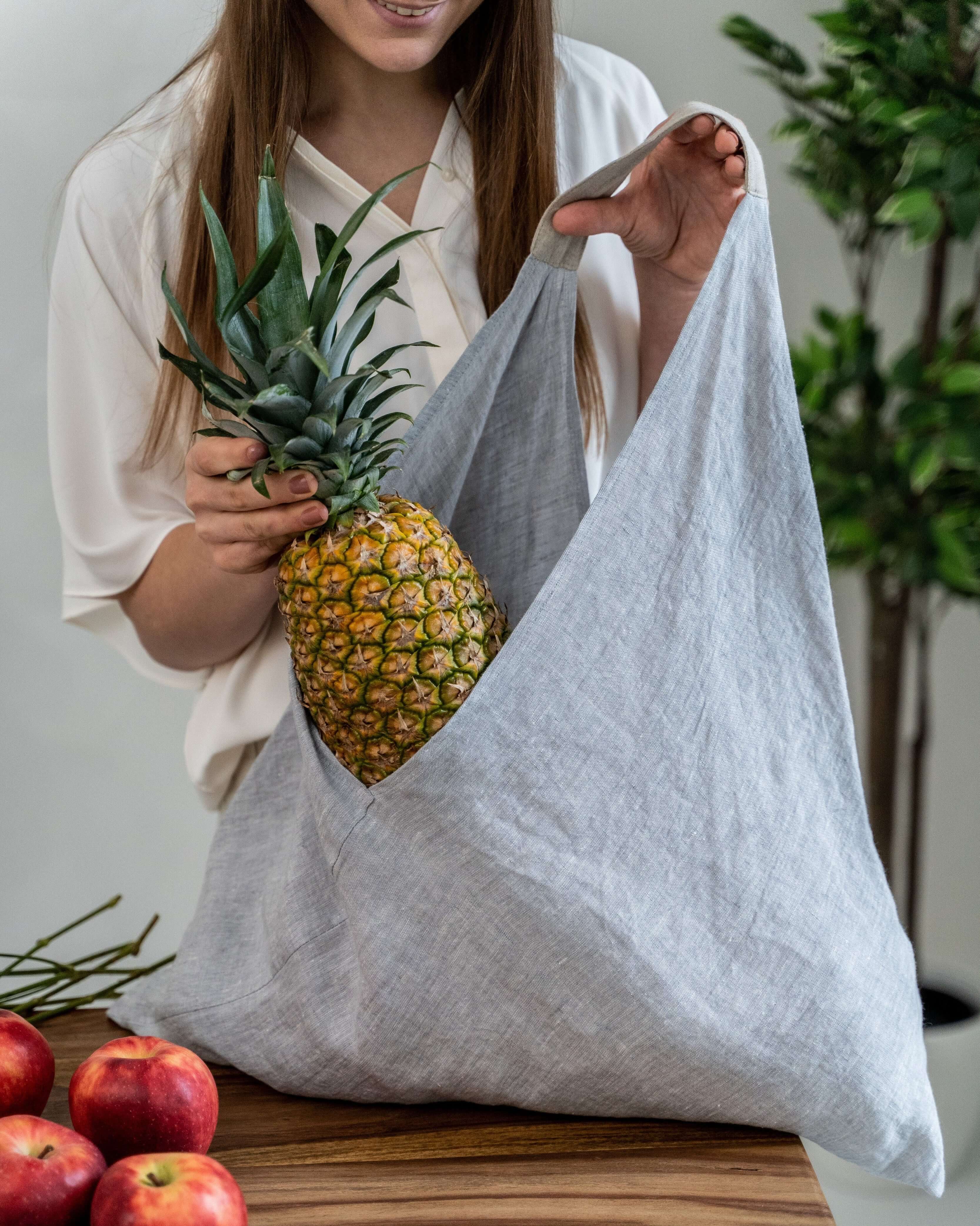 Woman carrying large linen tote bag outdoors, lifestyle photo
