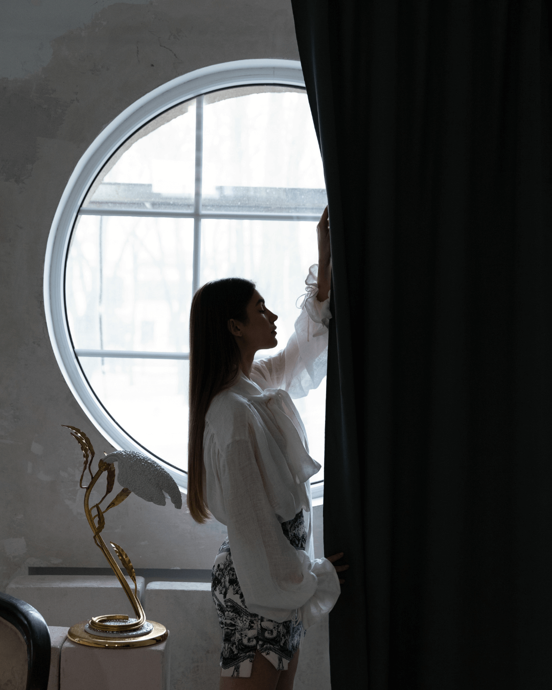 Woman holding safari green linen blackout curtain at window