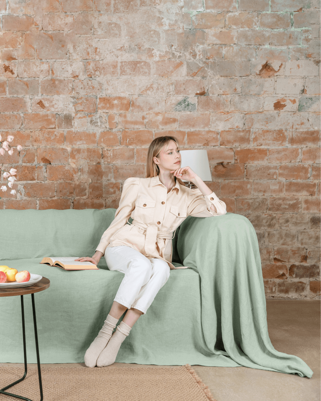 Woman with coffee on sofa with sage green linen L shaped sofa cover