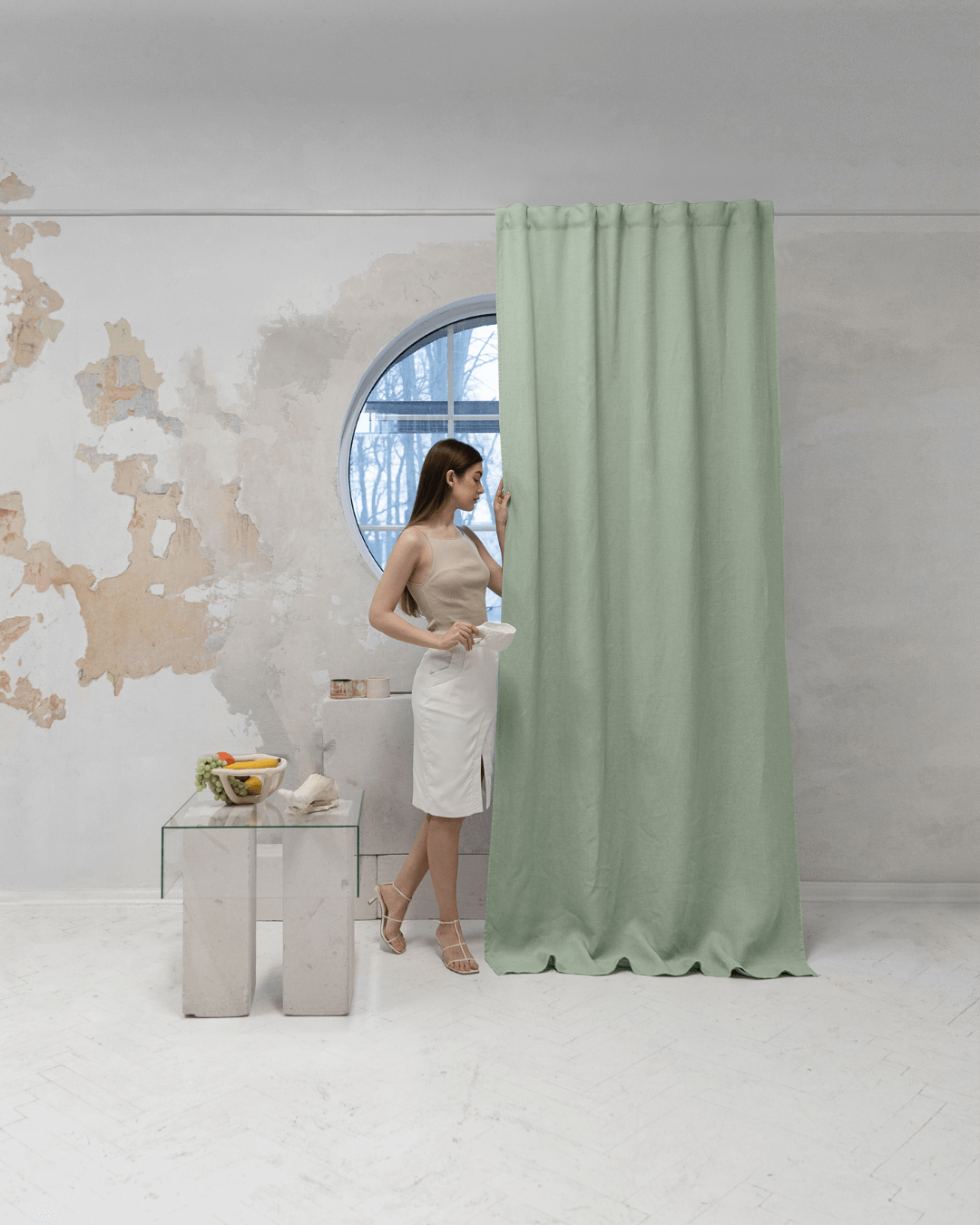 Woman in front of sage green linen blackout curtain, full length view