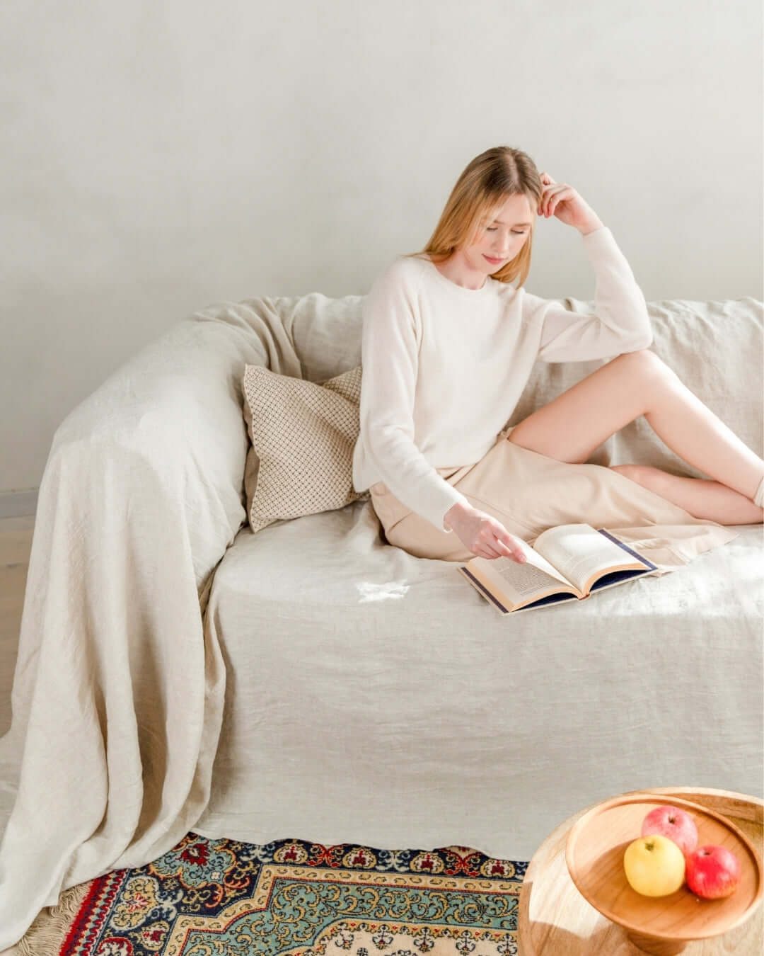 Woman reading on sofa with natural light linen couch slipcover
