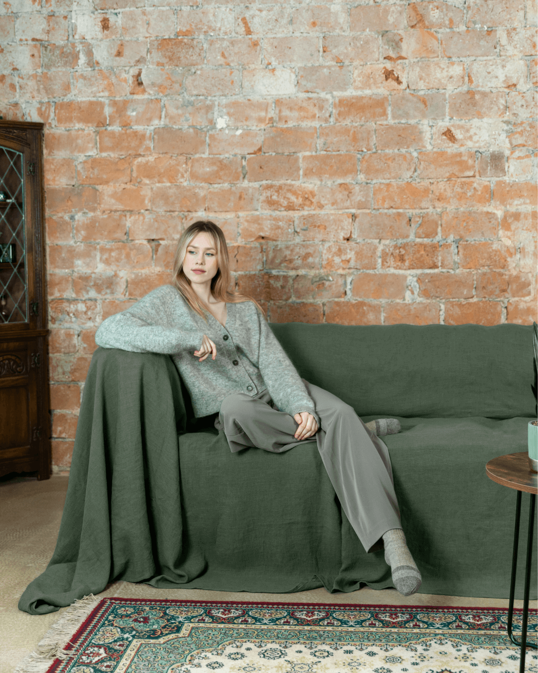 Woman relaxing on sofa with safari green linen sofa cover for oversized sofa