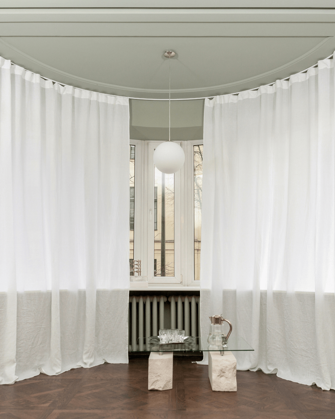 White linen curtains in living room with glass table, full length view