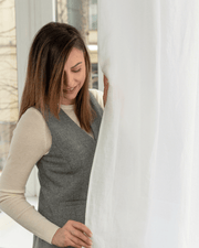 Woman beside white semi-sheer linen curtain panel, 175 g/m²